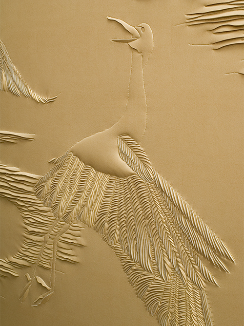 Detail of hand-sculpted gold faux suede artwork by Helen Amy Murray featuring cranes and clouds in a gold wooden frame