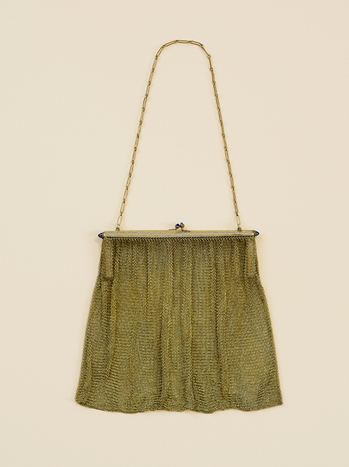 Photograph of a vintage metal clasp purse with metal chain handle on cream background