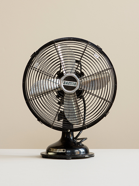 Photograph of an Original Cinni Black Desk Fan with silver blades on a white surface with cream background