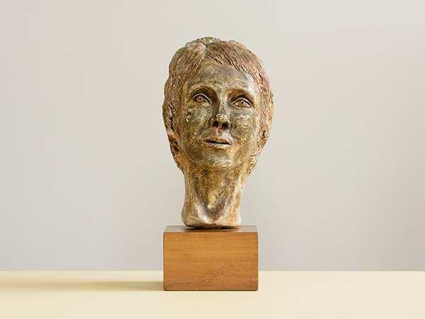 Plaster bust of a female head on a wooden block by Jane Murray against a cream background