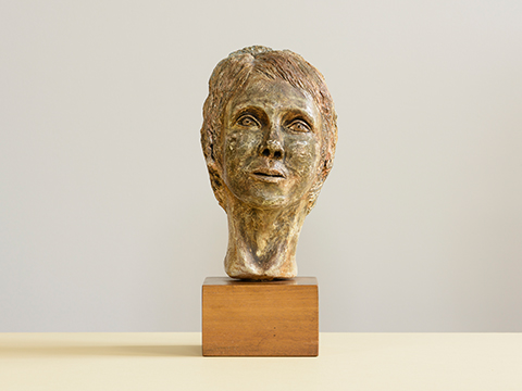 Plaster bust of a female head on a wooden block by Jane Murray against a cream background
